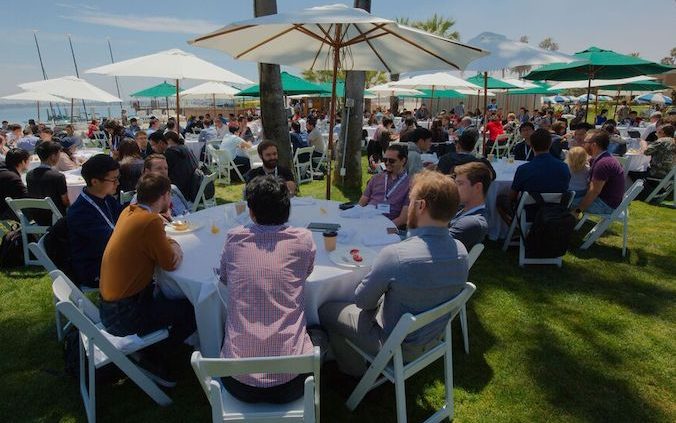 a group of people sitting outdoors at tables