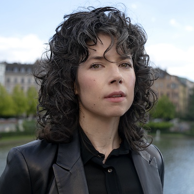 A woman with curly hair wearing a black jacket.