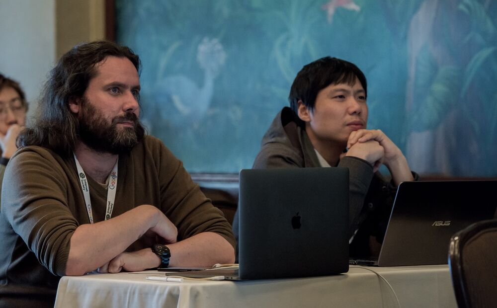 two men sitting and listening to speaker